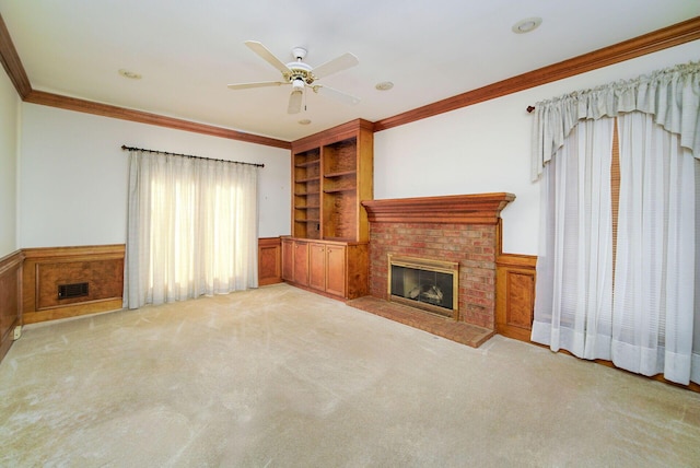 unfurnished living room featuring ornamental molding, light carpet, ceiling fan, and a fireplace