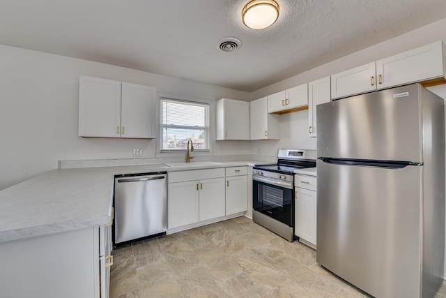 kitchen with sink, a textured ceiling, white cabinets, and appliances with stainless steel finishes