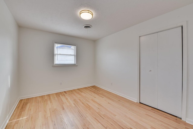 unfurnished bedroom featuring a closet, a textured ceiling, and light wood-type flooring