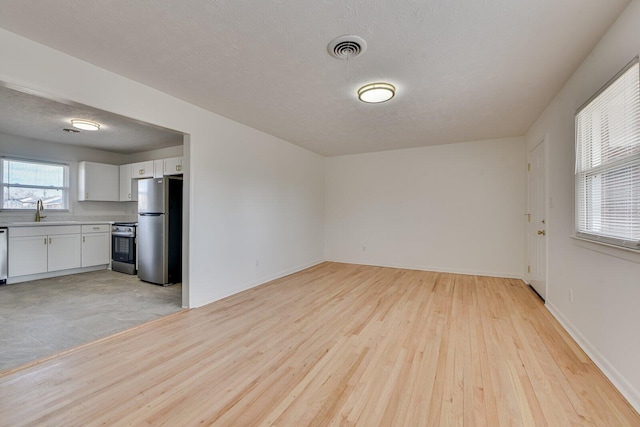 empty room featuring sink, light hardwood / wood-style floors, and a textured ceiling