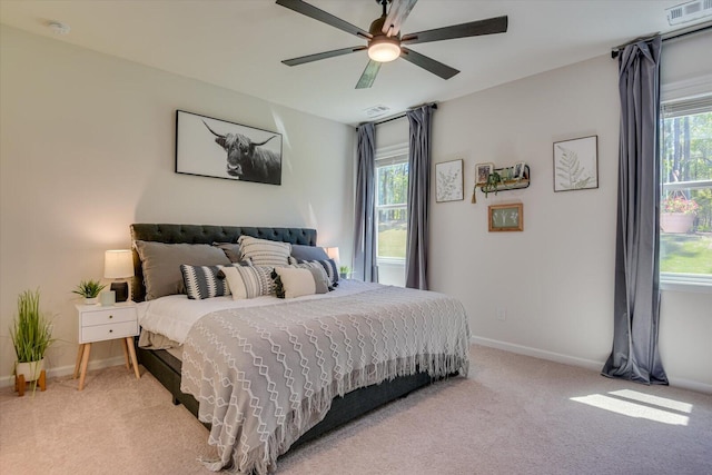 bedroom with baseboards, visible vents, a ceiling fan, and light colored carpet
