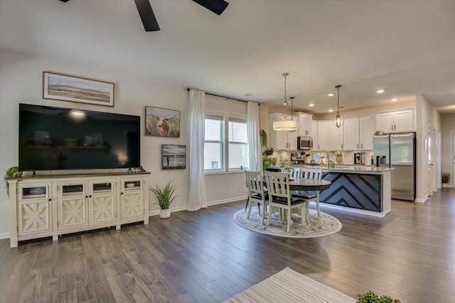 living area with baseboards, ceiling fan, and dark wood finished floors