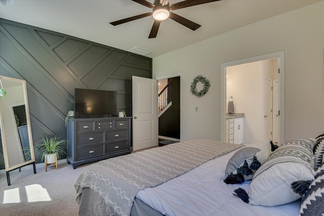 bedroom with connected bathroom, a decorative wall, ceiling fan, carpet flooring, and visible vents