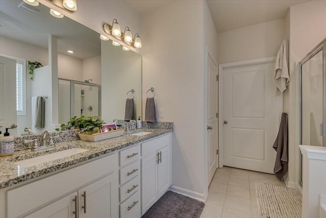 bathroom with double vanity, tile patterned flooring, a stall shower, and a sink