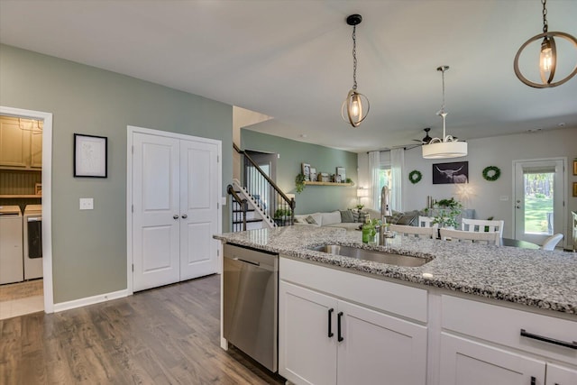 kitchen with stainless steel dishwasher, white cabinets, a sink, light stone countertops, and separate washer and dryer