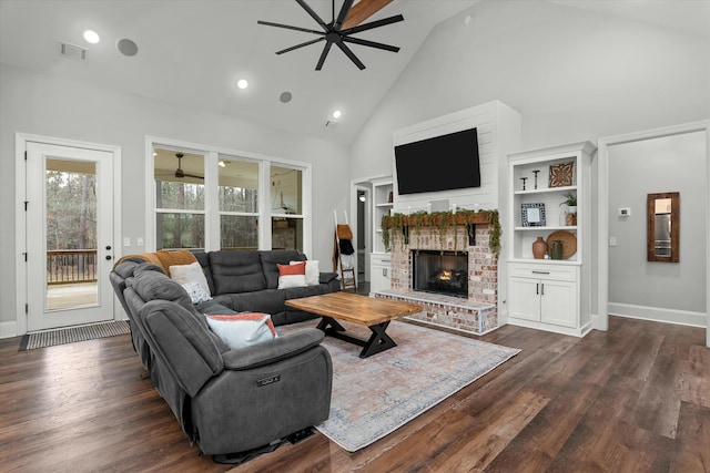 living room featuring dark wood-type flooring, ceiling fan, a fireplace, and high vaulted ceiling