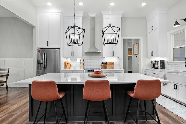 kitchen with white cabinetry, decorative light fixtures, a center island, appliances with stainless steel finishes, and dark hardwood / wood-style floors