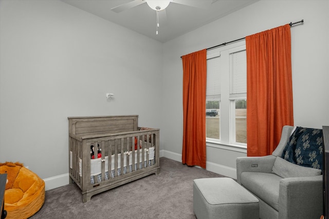 bedroom featuring a nursery area, ceiling fan, and carpet floors