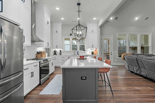 kitchen with a kitchen bar, decorative light fixtures, a center island, stainless steel appliances, and white cabinets