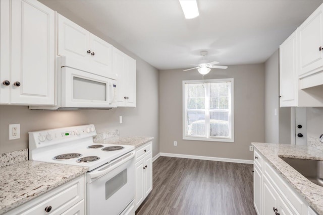 kitchen with white appliances, dark wood-style floors, baseboards, a sink, and white cabinets