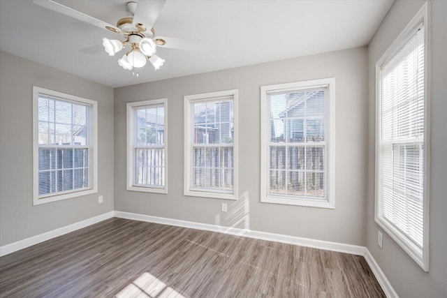 unfurnished dining area featuring baseboards, wood finished floors, and a ceiling fan