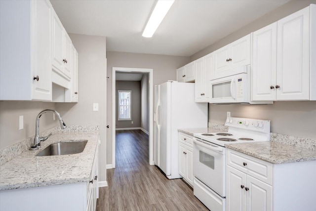 kitchen featuring baseboards, light wood-style flooring, white cabinets, white appliances, and a sink