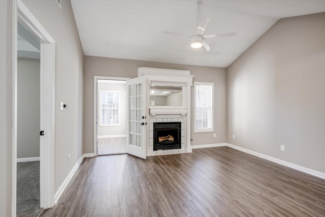 unfurnished living room featuring a ceiling fan, baseboards, lofted ceiling, a fireplace, and dark wood-style flooring