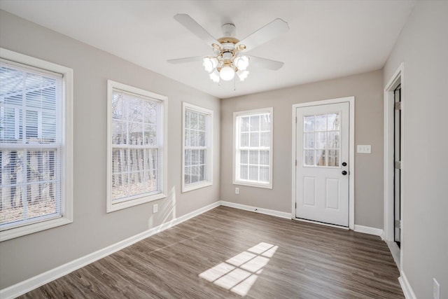 interior space featuring ceiling fan, baseboards, and dark wood finished floors