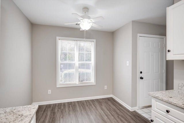 unfurnished dining area featuring a ceiling fan, baseboards, and wood finished floors