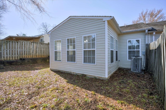 view of property exterior with central AC and fence