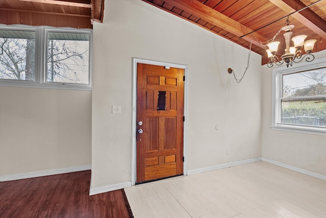 foyer featuring baseboards, wooden ceiling, beamed ceiling, wood finished floors, and a notable chandelier