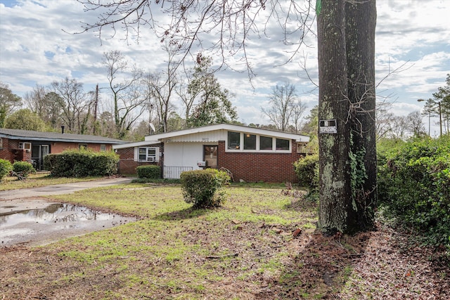 view of front facade featuring driveway, a front lawn, and brick siding