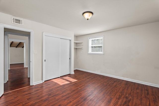 unfurnished bedroom featuring baseboards, a closet, visible vents, and wood finished floors