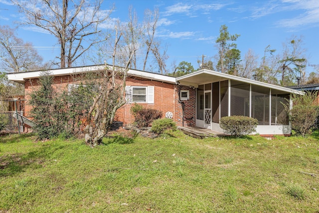 view of front of home featuring brick siding, a front yard, and a sunroom