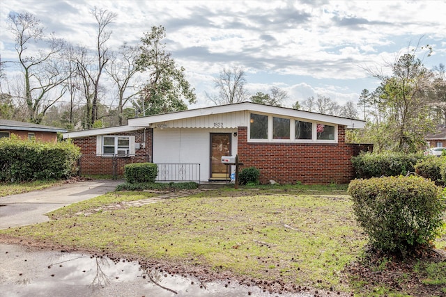 view of front of property with concrete driveway, brick siding, and a front lawn