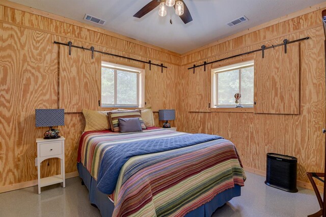 bedroom with ceiling fan, wood walls, and multiple windows