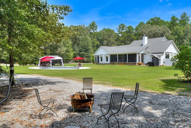 view of yard with a gazebo, a fire pit, and a sunroom