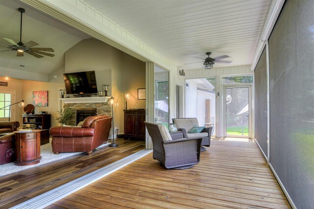 wooden terrace with a stone fireplace and ceiling fan