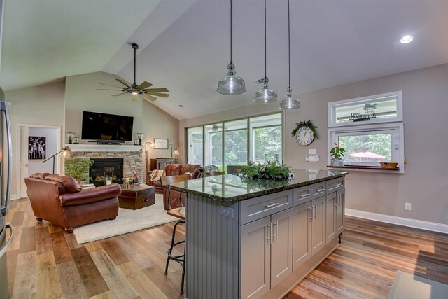 kitchen featuring a center island, dark stone counters, a kitchen breakfast bar, hanging light fixtures, and gray cabinets