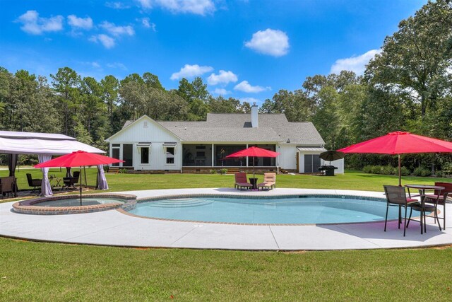 1370 Deerwood Cir, Stapleton, GA 30823 - view of swimming pool featuring a yard, a pool with connected hot tub, a sunroom, and a patio area