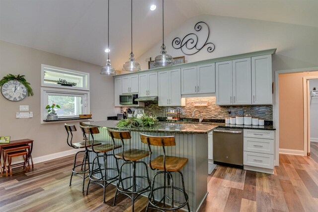 kitchen featuring dishwasher, a center island, hanging light fixtures, backsplash, and dark stone counters