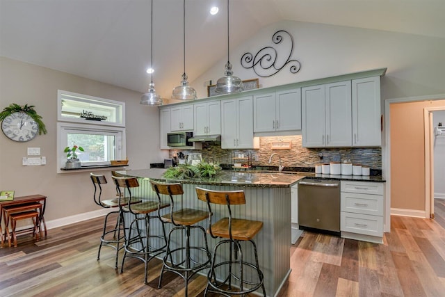 1370 Deerwood Cir, Stapleton, GA 30823 - kitchen with appliances with stainless steel finishes, a kitchen bar, backsplash, wood finished floors, and under cabinet range hood