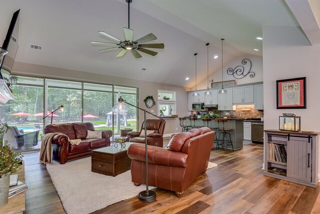 living room with ceiling fan, light wood-type flooring, and vaulted ceiling