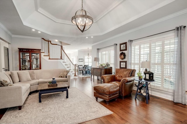 living room featuring a chandelier, stairs, a tray ceiling, and hardwood / wood-style flooring