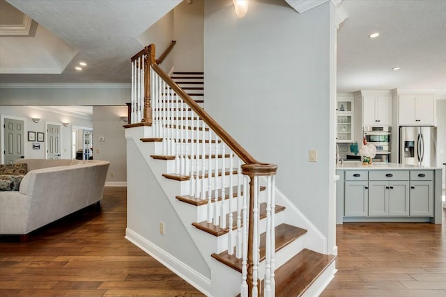 stairway featuring recessed lighting, baseboards, wood-type flooring, and ornamental molding