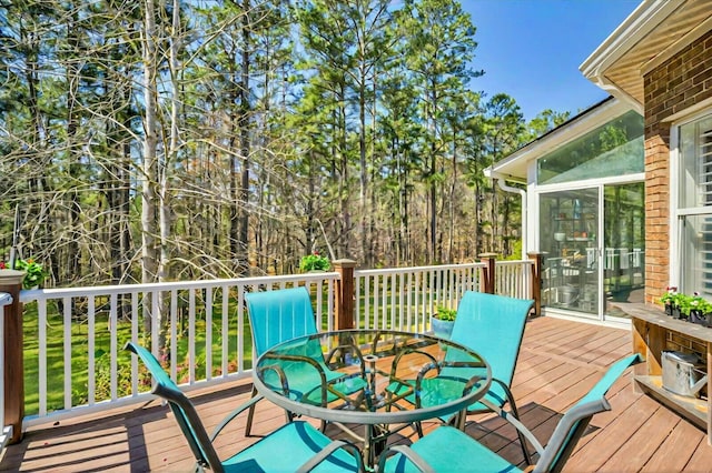 deck with outdoor dining space and a sunroom