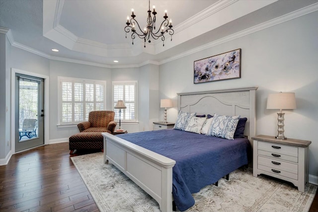 bedroom with a notable chandelier, multiple windows, a raised ceiling, and wood finished floors