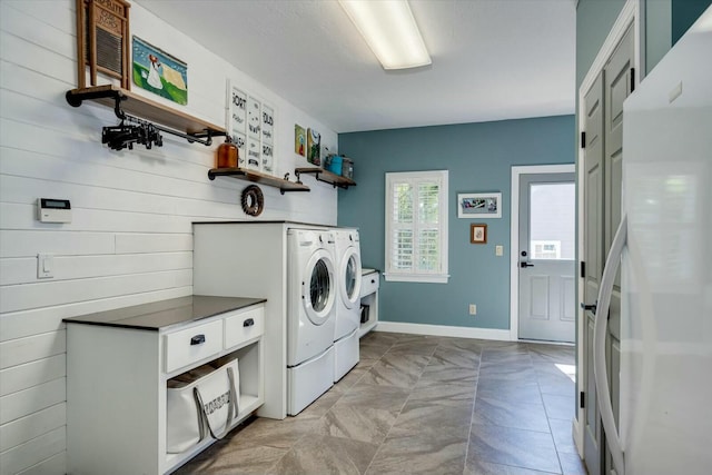 clothes washing area featuring baseboards, independent washer and dryer, and laundry area