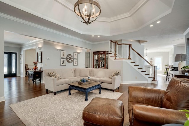 living area with baseboards, dark wood finished floors, stairs, a tray ceiling, and a notable chandelier