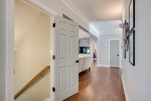 hall featuring crown molding, baseboards, and hardwood / wood-style floors