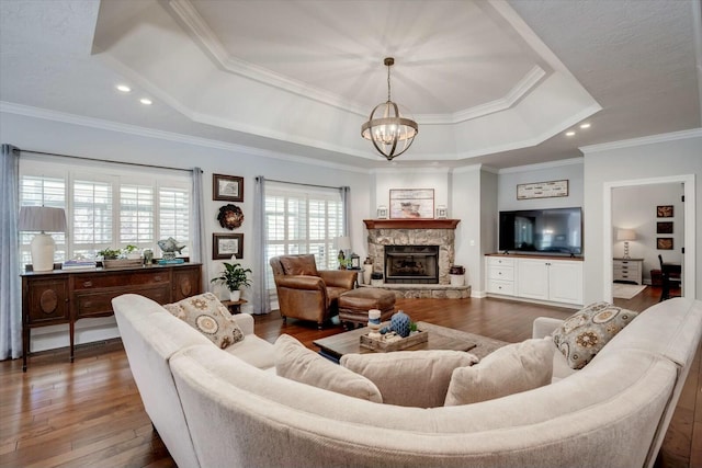 living room featuring an inviting chandelier, a raised ceiling, hardwood / wood-style flooring, and ornamental molding