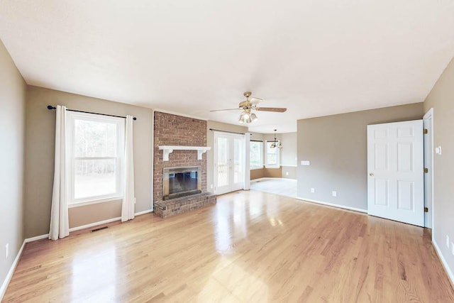 unfurnished living room featuring light wood-type flooring, a fireplace, visible vents, and a ceiling fan