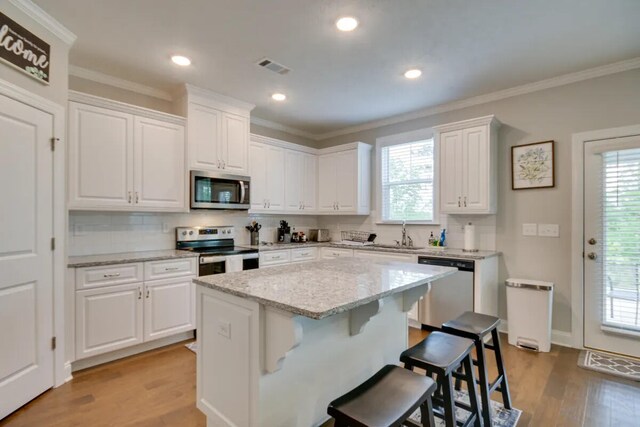 3120 Wayne Dr, Evans, GA 30809 - kitchen featuring appliances with stainless steel finishes, light wood-style floors, a breakfast bar area, white cabinetry, and ornamental molding