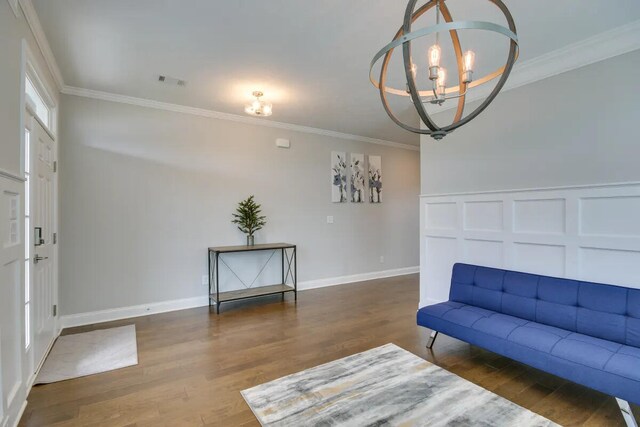 3120 Wayne Dr, Evans, GA 30809 - living area featuring a chandelier, wood finished floors, crown molding, a decorative wall, and baseboards