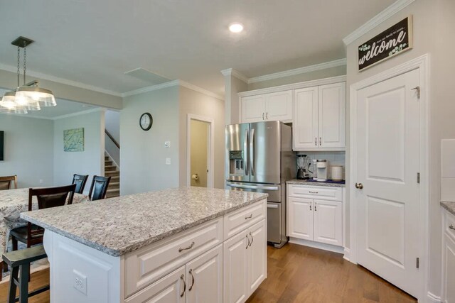 3120 Wayne Dr, Evans, GA 30809 - kitchen with stainless steel fridge with ice dispenser, ornamental molding, dark wood-type flooring, white cabinetry, and a center island
