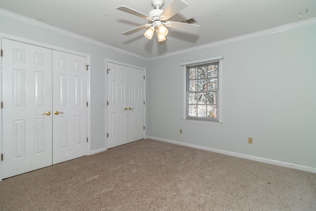 unfurnished bedroom featuring crown molding, light carpet, and two closets