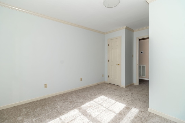 empty room featuring crown molding and light colored carpet