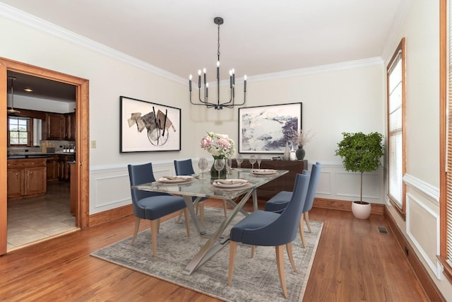 dining space with hardwood / wood-style flooring, ornamental molding, and a chandelier