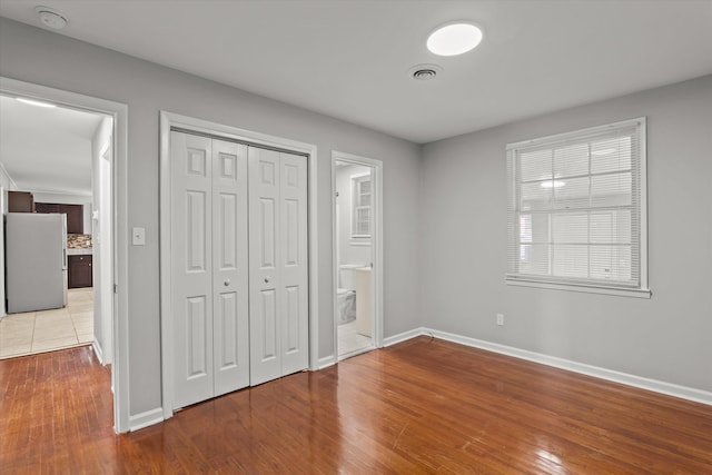 2131 Reedale Ave, Augusta, GA 30906 - unfurnished bedroom with freestanding refrigerator, baseboards, wood finished floors, a closet, and ensuite bath