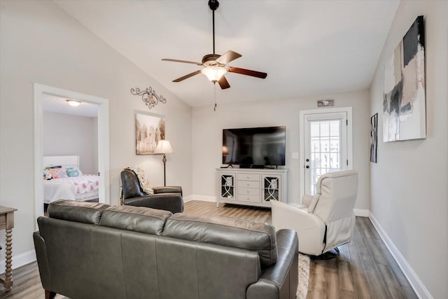 living room featuring ceiling fan, vaulted ceiling, and wood-type flooring